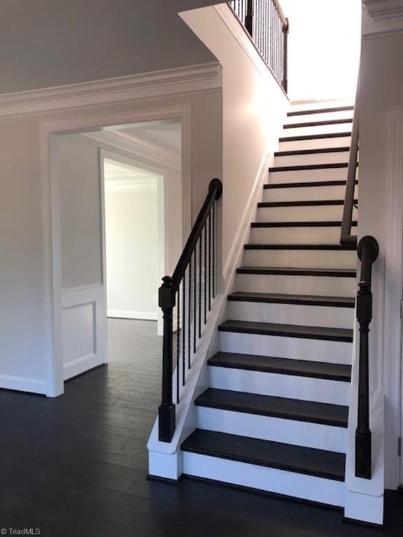 stairs with ornamental molding and hardwood / wood-style floors