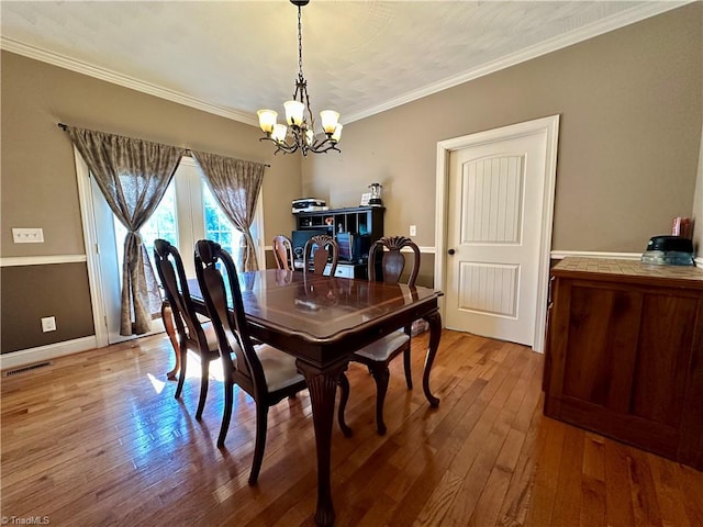 dining area featuring ornamental molding, hardwood / wood-style floors, and a notable chandelier