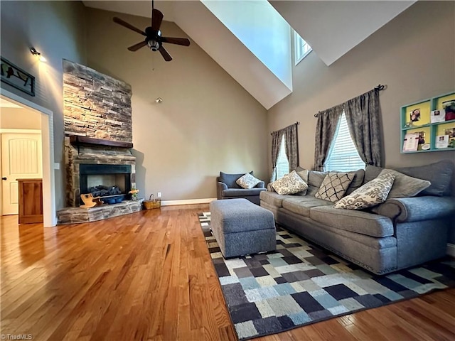 living room featuring a fireplace, wood-type flooring, high vaulted ceiling, and ceiling fan