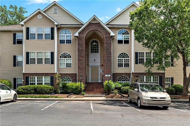view of property featuring brick siding and uncovered parking