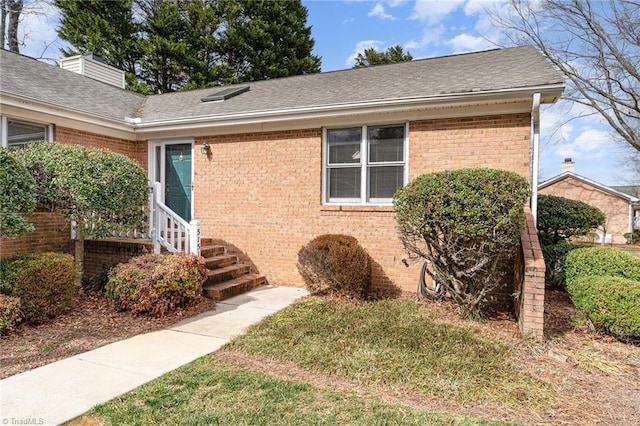 view of side of home featuring brick siding and a shingled roof