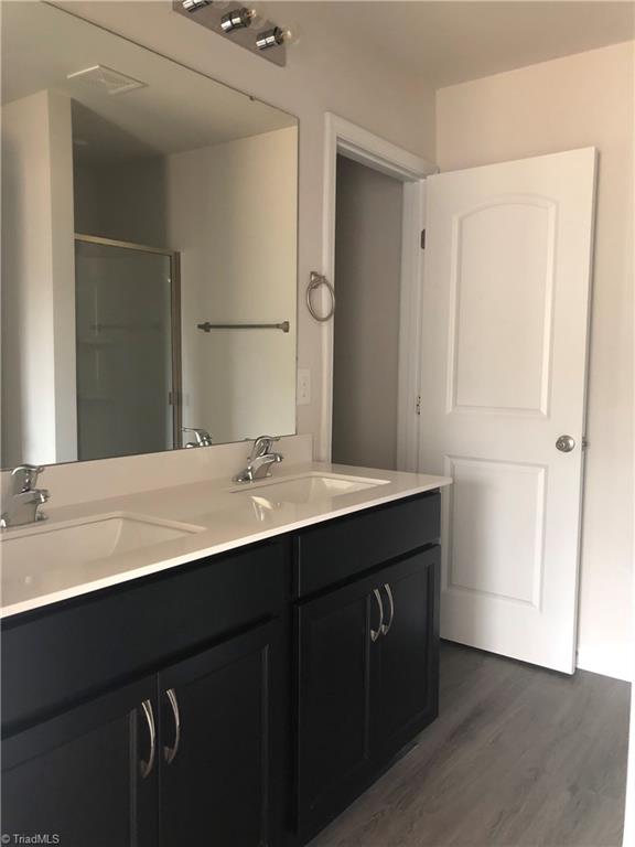 2892 Tysinger Rd, Denton, NC 27239 - full bath featuring double vanity, wood finished floors, and a stall shower