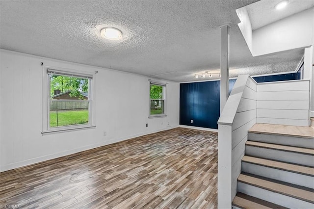basement with plenty of natural light, a textured ceiling, and wood finished floors