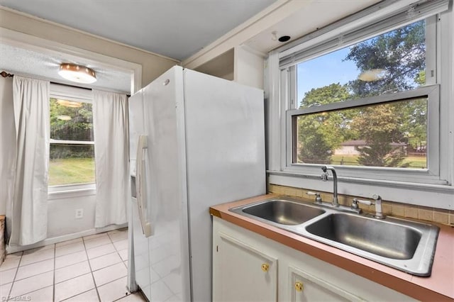 interior space featuring a sink, light tile patterned floors, and a healthy amount of sunlight