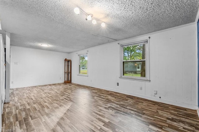 spare room featuring a textured ceiling, plenty of natural light, and wood finished floors