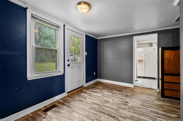 entryway with crown molding, baseboards, wood finished floors, and visible vents