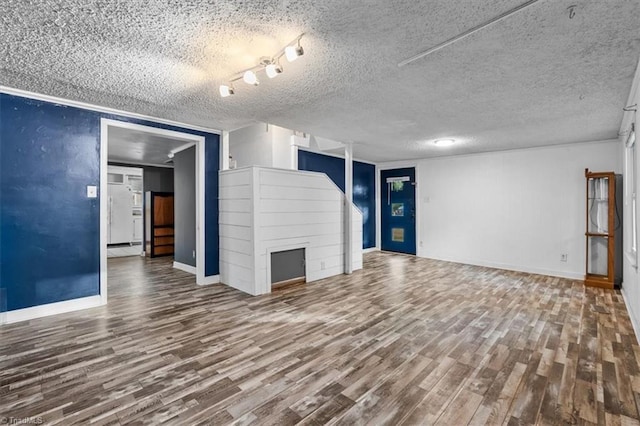unfurnished living room with baseboards, a textured ceiling, and wood finished floors
