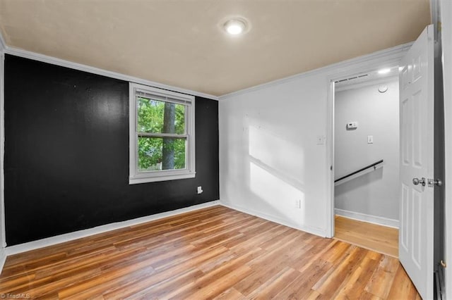 empty room featuring baseboards, ornamental molding, and wood finished floors