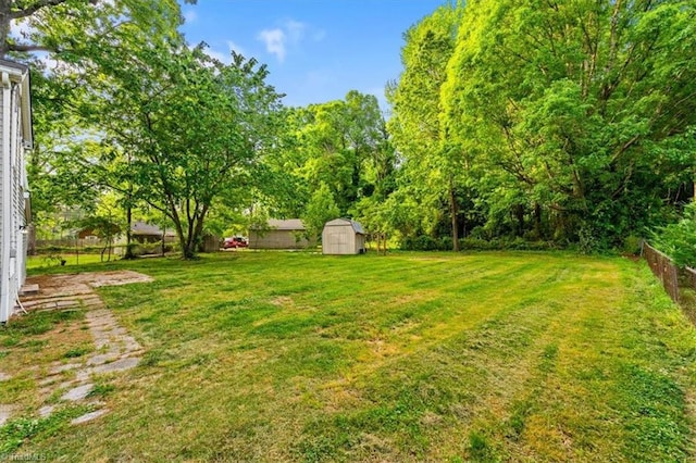 view of yard featuring a storage unit, fence, and an outbuilding