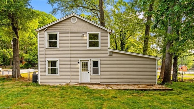 rear view of house with a lawn, fence, and cooling unit