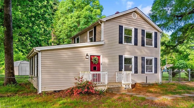 traditional home with a storage shed, fence, and an outbuilding
