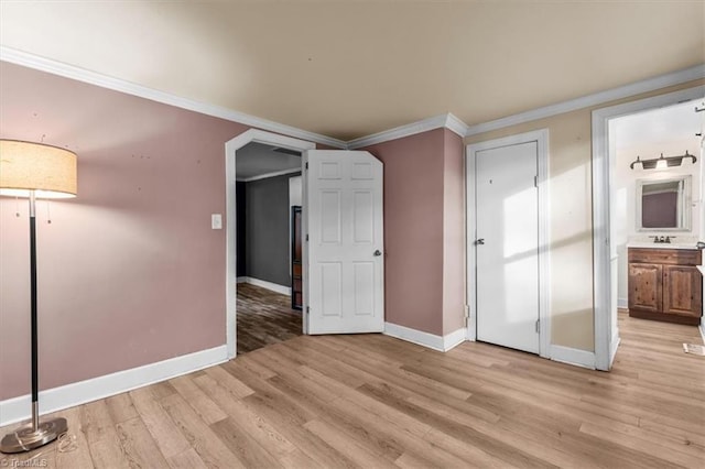 unfurnished room with crown molding, baseboards, arched walkways, and light wood-style flooring