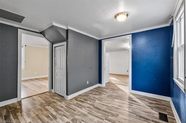 unfurnished bedroom featuring visible vents, baseboards, crown molding, and wood finished floors