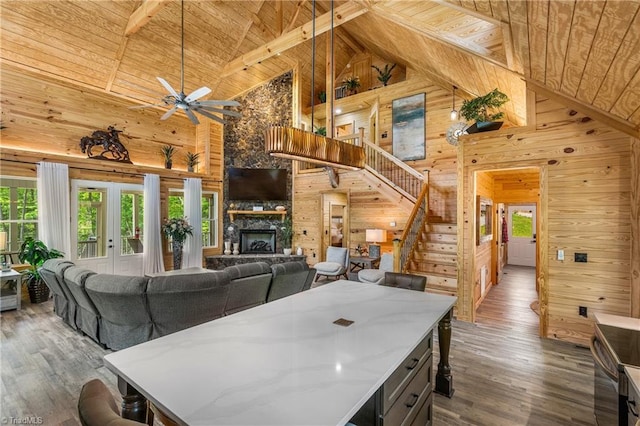 dining space featuring high vaulted ceiling, wood ceiling, wooden walls, wood finished floors, and stairway