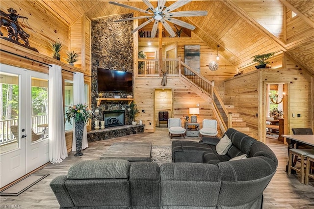 living room with wooden ceiling, wooden walls, high vaulted ceiling, stairway, and a ceiling fan