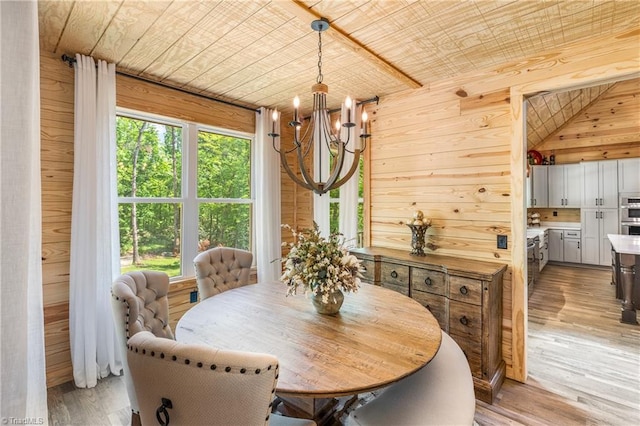dining room featuring a chandelier, light wood-type flooring, wooden walls, and wood ceiling