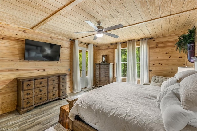 bedroom featuring wood ceiling, wood walls, wood finished floors, and a ceiling fan