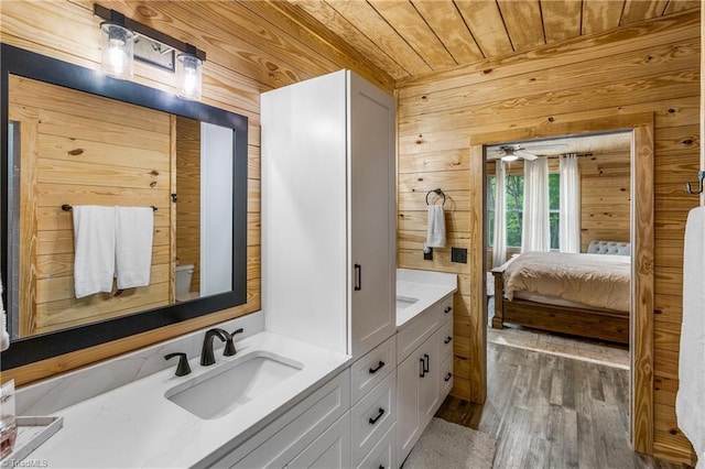 full bathroom featuring wood ceiling, connected bathroom, double vanity, wood finished floors, and wooden walls
