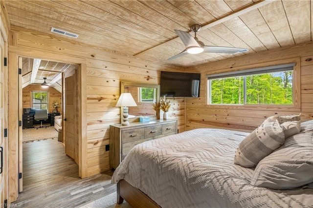 bedroom featuring wood ceiling, wooden walls, multiple windows, light wood-style flooring, and an office area