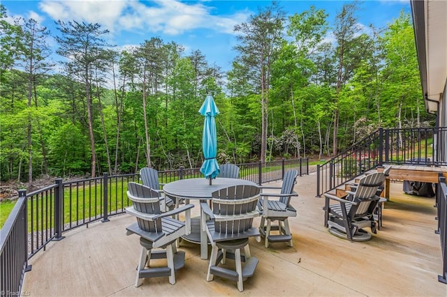 view of patio featuring outdoor dining area and a forest view