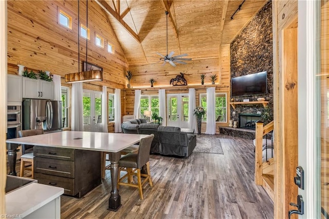 dining room featuring french doors, high vaulted ceiling, dark wood-type flooring, wooden ceiling, and a fireplace