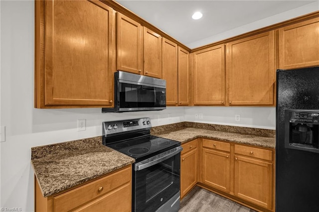 kitchen with dark stone counters, recessed lighting, brown cabinets, and stainless steel appliances