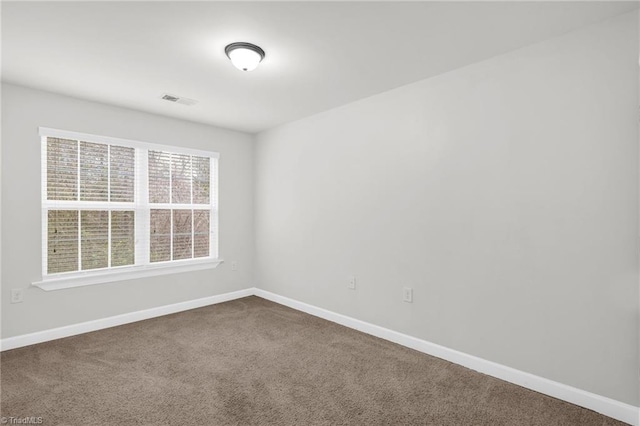 empty room with visible vents, baseboards, and dark colored carpet