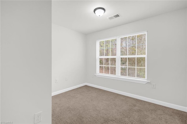 carpeted spare room with visible vents and baseboards