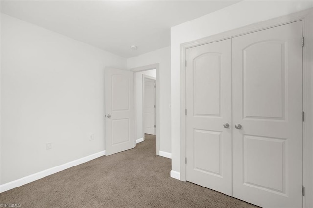 unfurnished bedroom featuring a closet, carpet floors, and baseboards