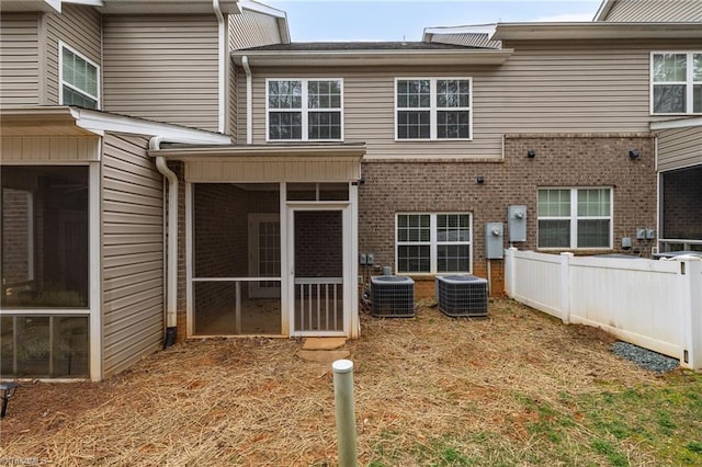 back of house with brick siding, cooling unit, fence, and a sunroom