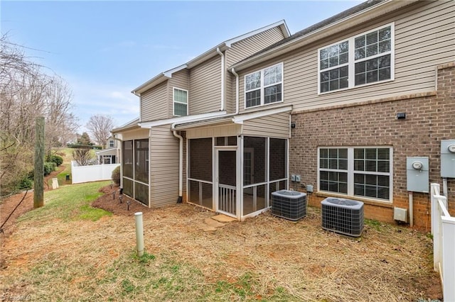 rear view of house featuring cooling unit, brick siding, and a sunroom