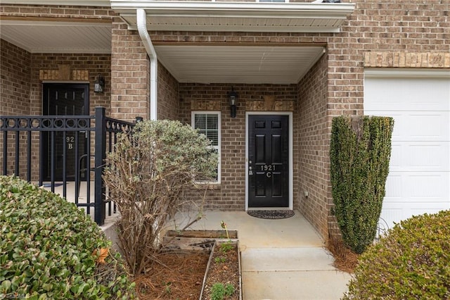 doorway to property featuring brick siding, covered porch, and an attached garage