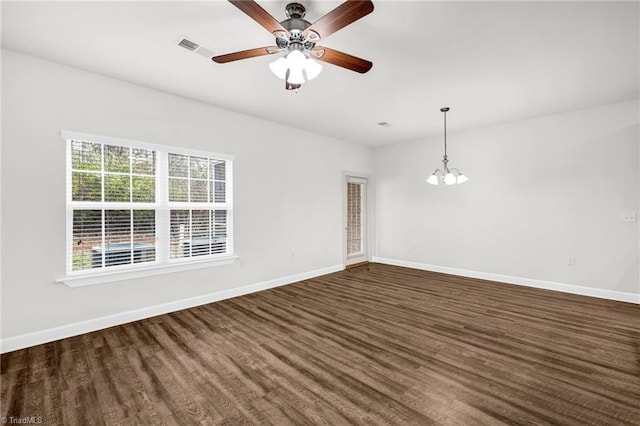 empty room with dark wood finished floors, visible vents, ceiling fan with notable chandelier, and baseboards