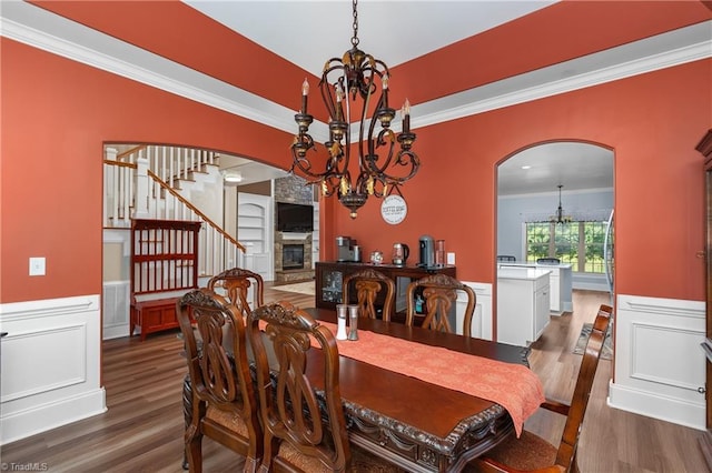 6147 Olde Fields Way, Pfafftown, NC 27040 - dining room with a chandelier, arched walkways, wood finished floors, ornamental molding, and a wainscoted wall
