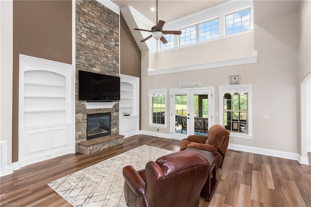 6147 Olde Fields Way, Pfafftown, NC 27040 - living room with a high ceiling, wood finished floors, a ceiling fan, a stone fireplace, and built in shelves
