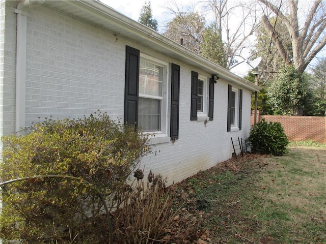 view of home's exterior with fence and brick siding