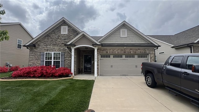 craftsman inspired home featuring a front yard, driveway, stone siding, and an attached garage