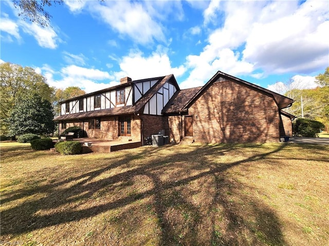 back of house with central AC unit and a lawn