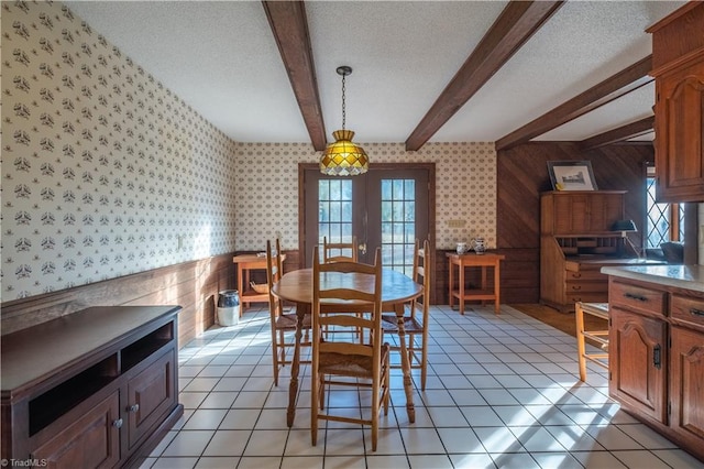 dining area featuring beamed ceiling, plenty of natural light, a textured ceiling, and french doors