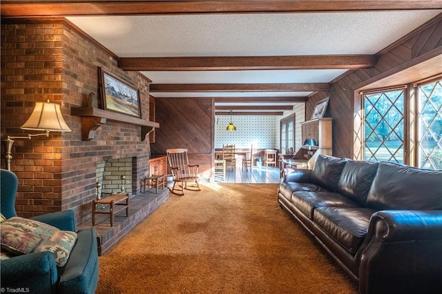 carpeted living room with wood walls, beamed ceiling, a textured ceiling, and a brick fireplace