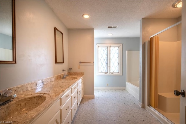 bathroom with plus walk in shower, vanity, and a textured ceiling