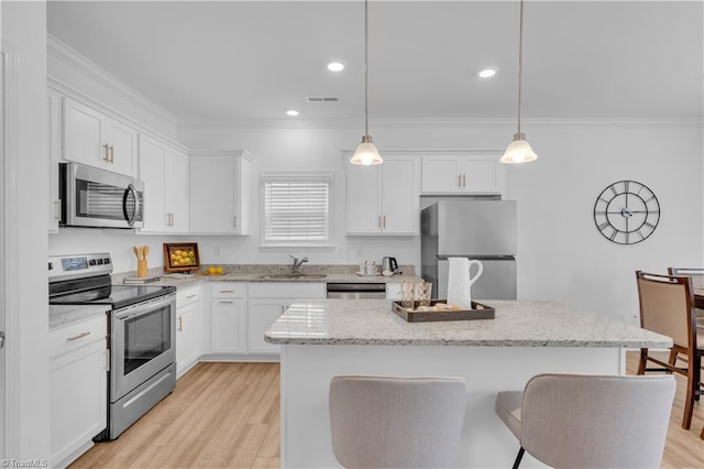 817 Sage Hill Dr, Jamestown, NC 27282 - kitchen featuring appliances with stainless steel finishes, ornamental molding, a kitchen breakfast bar, white cabinetry, and a center island