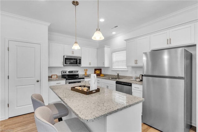 817 Sage Hill Dr, Jamestown, NC 27282 - kitchen featuring appliances with stainless steel finishes, white cabinets, ornamental molding, a kitchen island, and a breakfast bar area