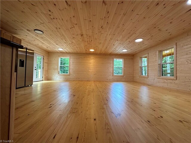 interior space with light hardwood / wood-style flooring, a wealth of natural light, and wooden ceiling