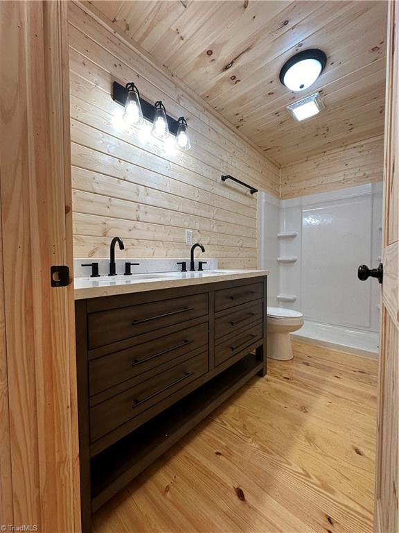 bathroom with vanity, a shower, wooden ceiling, and wooden walls