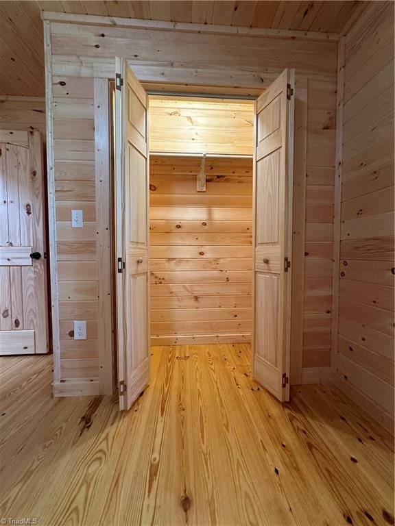 corridor featuring wooden walls and light wood-type flooring