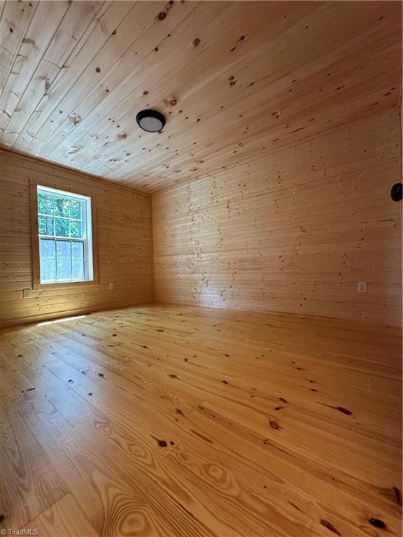 empty room with wooden ceiling, wooden walls, and light hardwood / wood-style flooring