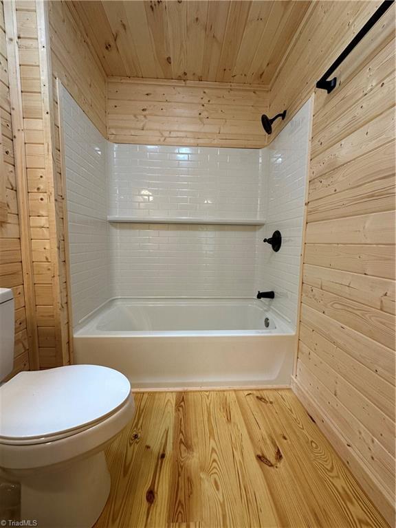 bathroom with wood walls, hardwood / wood-style floors, wooden ceiling, and toilet