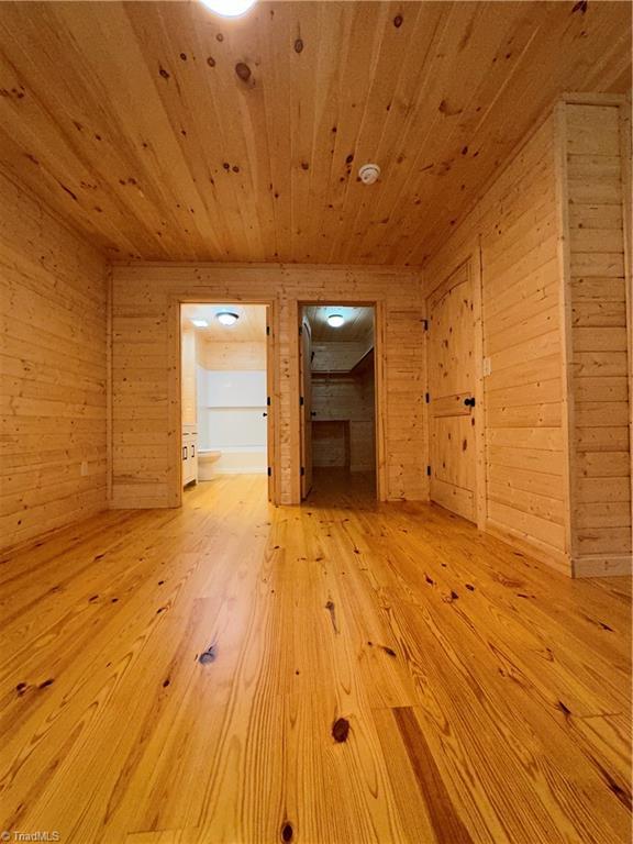 unfurnished living room featuring wood walls and wooden ceiling