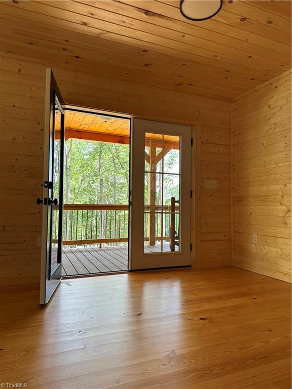 entryway featuring light wood-type flooring, wooden walls, and wooden ceiling